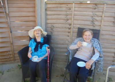 Two residents enjoying a cup of tea in the garden at the Old Downs Residential Care Home