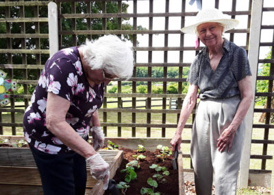 Two lady residents at The Old Downs Residential Care Home tending to plants in the garden