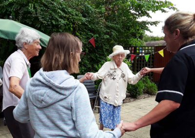 Residents and staff dancing at the summer BBQ in the garden at The Old Downs