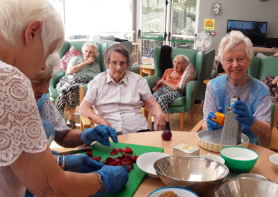 Lady residents making fruit crumble at The Old Downs Residential Care Home