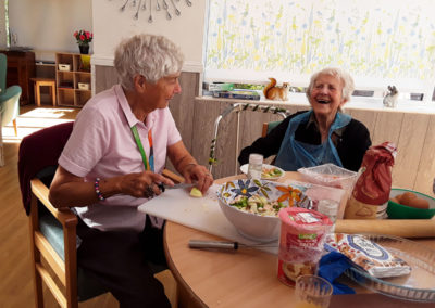 Toe lady residents laughing whilst preparing quiche ingredients