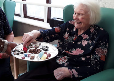 Lady resident smiling as she picks sweets from a tray