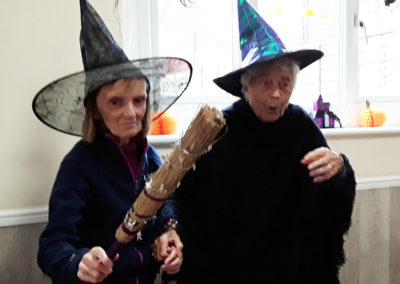 Lady residents at The Old Downs dressed as witches with a broomstick