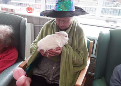 Lady resident cuddling the Magician's white rabbit