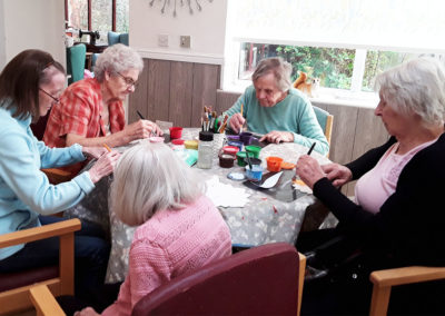 Residents at The Old Downs around a table working on a collective arts project