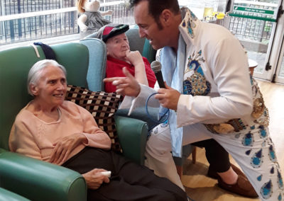 Elvis tribute singer interacting with a lady resident in her chair