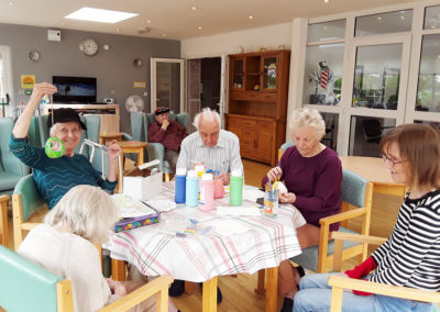 Residents painting bird feeders together at The Old Downs Residential Care Home