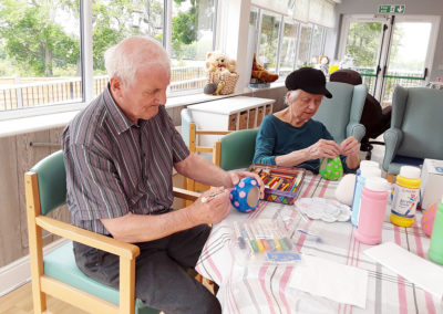 Residents enjoying painting bird feeders at The Old Downs Residential Care Home