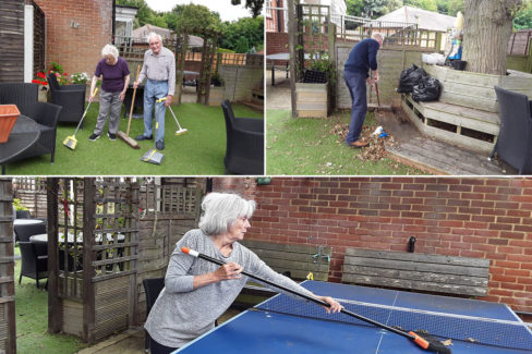 Residents sweeping leaves and tidying in the garden at The Old Downs