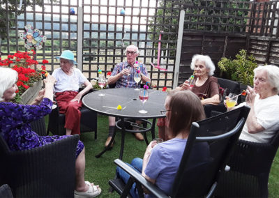 A group of residents in the garden drinking Prosecco cocktails at The Old Downs