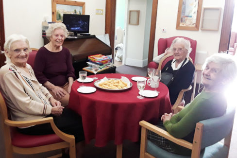 Lady residents enjoying cheese straws and wine at The Old Downs Residential Care Home