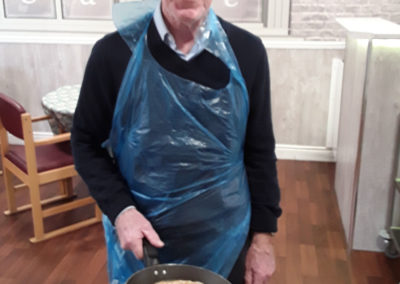 Resident flipping a pancake at The Old Downs Residential Care Home