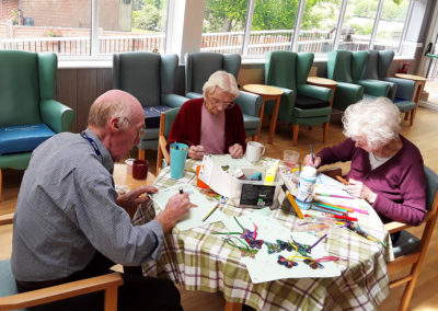 Residents painting butterfly sun catchers at The Old Downs Residential Care Home