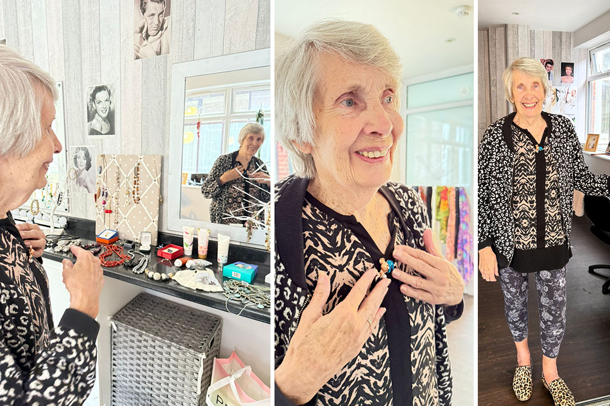 A resident at The Old Downs smiles while trying on jewellery and accessories in the Home’s pop-up shop, surrounded by displays of necklaces, scarves, and beauty items.