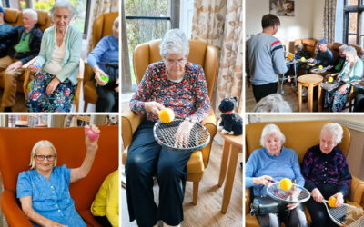 The Old Downs Residential Care Home residents enjoying a seated exercise session together, with tennis rackets and balls, and stress balls.